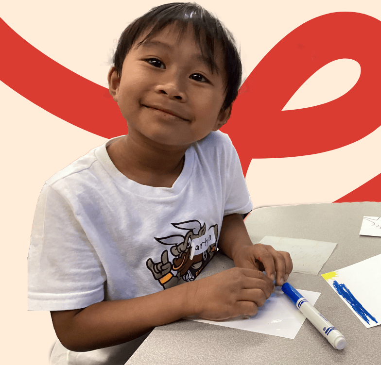 Photo of a LiftED program participant at a desk with markers and smiling at the camera
