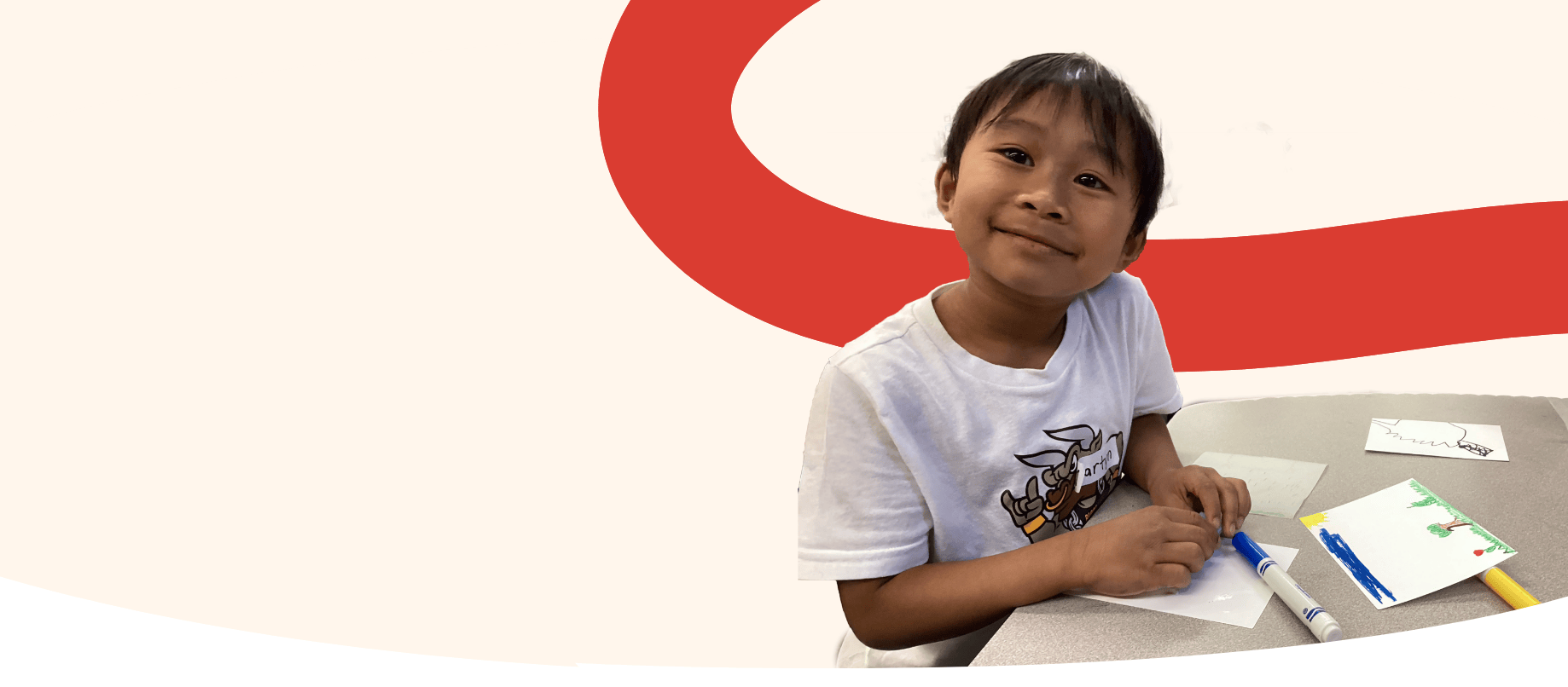 Photo of a LiftED program participant at a desk with markers and smiling at the camera