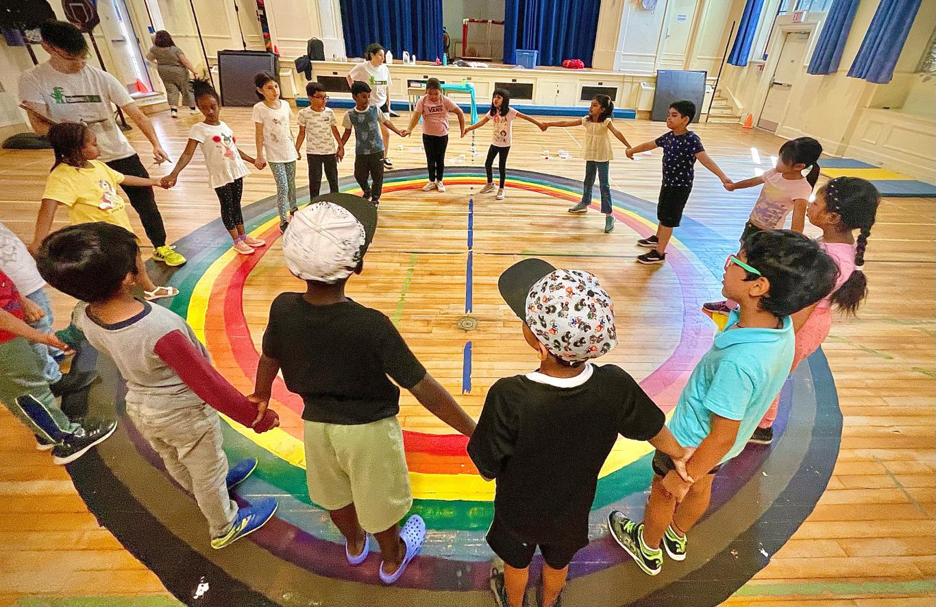 Photo of a group of LiftED program participants standing in a gym and holding hands in a circle