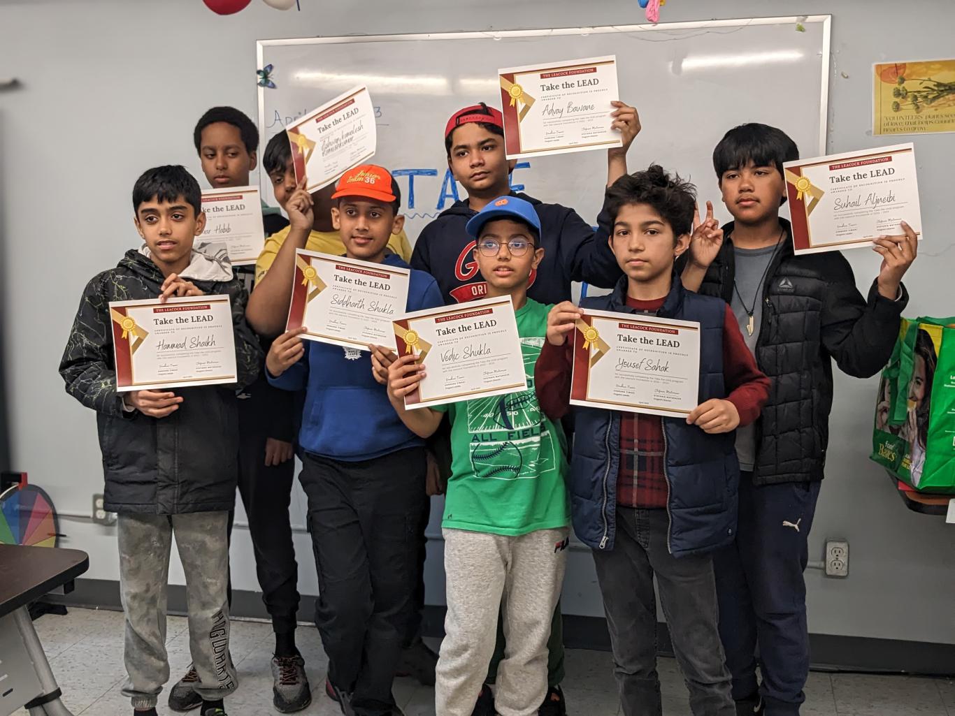 Photo of eight LiftED Take the LEAD program participants standing in a classroom and holding up program completion certificates